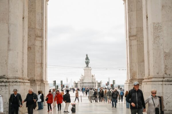 Crowd of people walking through archway towards Praça do Comércio in Lisbon.